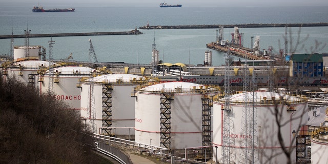 Oil storage tanks stand at the RN-Tuapsinsky refinery, operated by Rosneft Oil Co., as tankers sail beyond in Tuapse, Russia, on Monday, March 23, 2020.  Photographer: Andrey Rudakov/Bloomberg via Getty Images