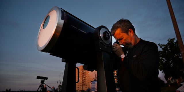 قام رئيس علماء الفلك في ساوث مين ، روبرت بورغيس ، بإعداد تلسكوب مزود بمرشحات شمسية لمراقبة الكسوف الجزئي من إيست بروم ، بورتلاند يوم الخميس ، 10 يونيو ، 2021.
