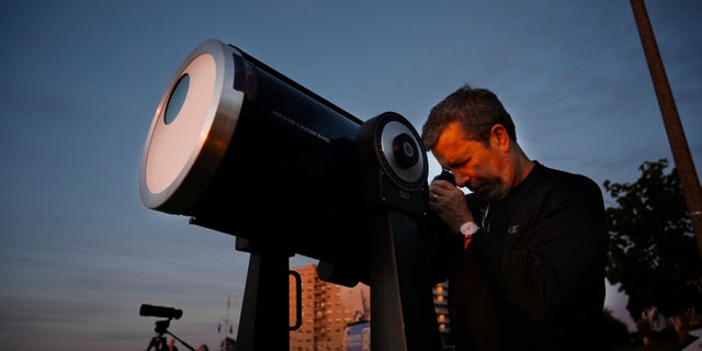 Robert Burgess, presidente de Southern Maine Astronomers, instala un telescopio con filtros solares para observar un eclipse parcial desde el Eastern Prom en Portland el jueves 10 de junio de 2021.