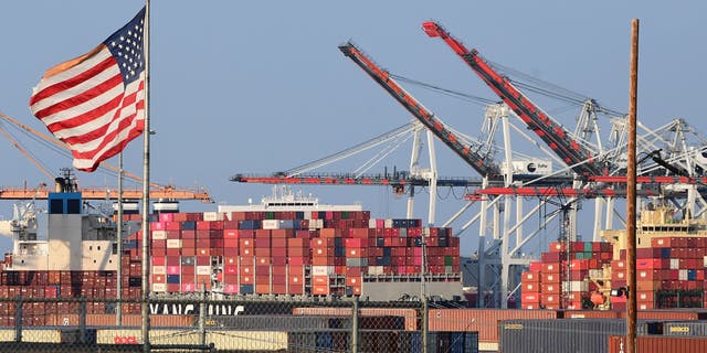 A U.S. flag flies near containers stacked high on a cargo ship at the Port of Los Angeles on September 28, 2021 in Los Angeles, California. (Photo by Frederic J. BROWN / AFP) (Photo by FREDERIC J. BROWN/AFP via Getty Images)