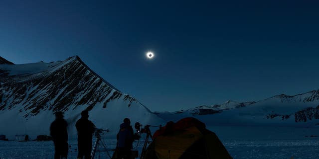 This handout picture released by Imagen Chile shows Chilean and US scientists looking at a solar eclipse from the Union Glacier in Antarctica on December 4, 2021.