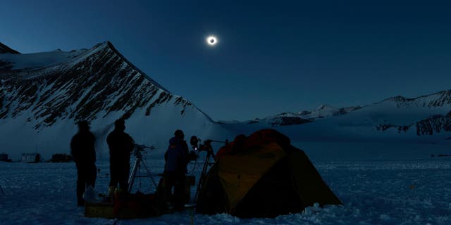 This handout picture released by Imagen Chile shows Chilean and US scientists looking at a solar eclipse from the Union Glacier in Antarctica on December 4, 2021.