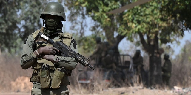 An Ivorian soldier provides security on arrival of Ivorian Prime Minister Patrick Achi at the launch of a vast aid plan for young people in regions bordering Mali and Burkina Faso where jihadist groups are trying to recruit, in Tougbo, on January 22, 2022.