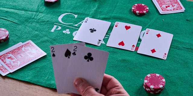 A person holds two deuces in their hand while playing poker.