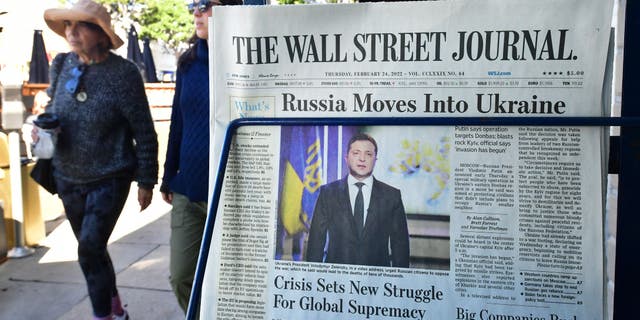 Pedestrians walk past a newspaper stand with copies of The Wall Street Journal and a front page report on Russia's invasion of Ukraine are being sold on February 24, 2022, in Los Angeles, California.