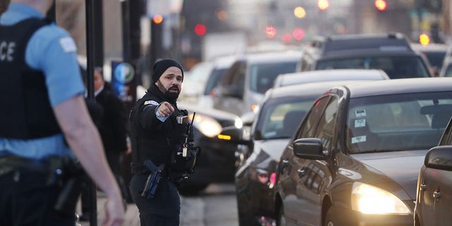 Police officers direct traffic as motorists line up for free gas at a BP station in Chicago on March 17, 2022. 