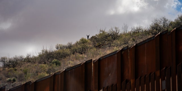 SASABE, ARIZONA - JANUARY 23: Migrants wait on the Mexican side for the U.S. Border Patrol agents to leave the border wall between the U.S. and Mexico to cross to an area where the wall is not complete near the city of Sasabe, Arizona, Sunday, January 23, 2022. (Photo by Salwan Georges/The Washington Post via Getty Images)