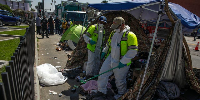 L.A. Sanitation Bureau crew clean up a homeless encampment on the sidewalk along Hollywood Blvd. on Tuesday, April 5, 2022 in Los Angeles , CA. 
