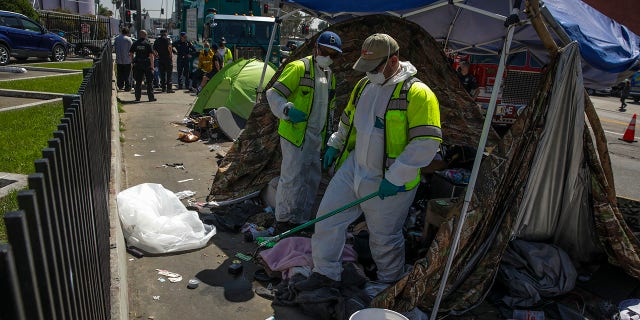 L.A. Sanitation Bureau crew clean up a homeless encampment on the sidewalk along Hollywood Blvd. on Tuesday, April 5, 2022 in Los Angeles , CA. 