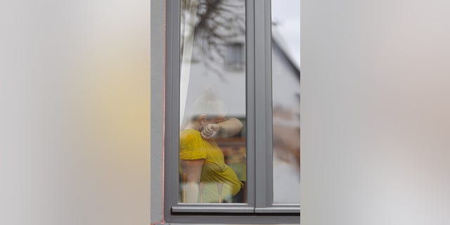 In this photo illustration a lonesome woman is sitting behind a window on April 08, 2022.