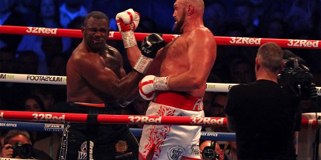 Britain's Tyson Fury (R) lands a punch to knockout Britain's Dillian Whyte in the sixth round and win their WBC heavyweight title fight at Wembley Stadium in west London, on April 23, 2022.
