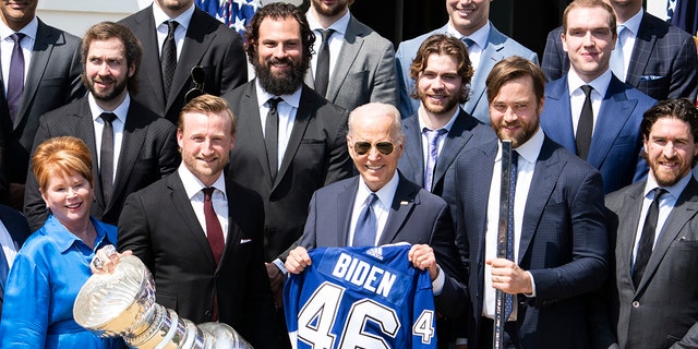 President Joe Biden holds a jersey during a ceremony with Tampa Bay Lightning to celebrate their 2020 and 2021 Stanley Cup championships at the White House, on Monday, April 25, 2022.