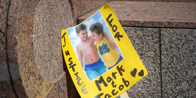 A sign shows an image of  Mark Iskander, 11, left, and his brother Jacob Iskander, 8, outside of Van Nuys Courthouse were a preliminary hearing was held for Rebecca Grossman who is charged with murder and other counts stemming from a crash in Westlake Village.