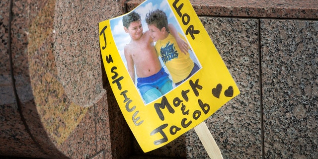 A sign shows an image of  Mark Iskander, 11, left, and his brother Jacob Iskander, 8, outside of Van Nuys Courthouse were a preliminary hearing was held for Rebecca Grossman.