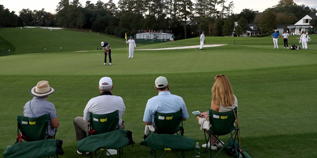Patrons look on as Dustin Johnson putts on the 9th green during the Masters on Nov. 12, 2020, in Augusta, Georgia.