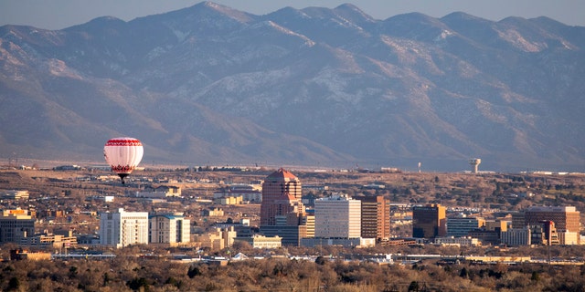 A hot air balloon floats over the skyscrapers of downtown Albuquerque, New Mexico.