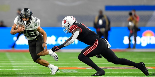 Travis Dye (26) of the Oregon Ducks runs the ball against Devin Lloyd of the Utah Utes during the third quarter of the PAC-12 Football Championship at Allegiant Stadium Dec. 3, 2021, in Las Vegas. 