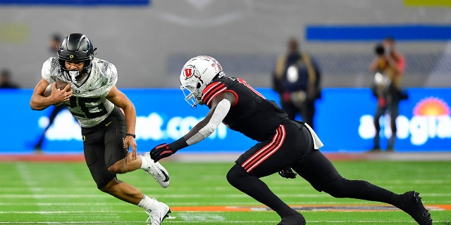 Travis Dye (26) of the Oregon Ducks runs the ball against Devin Lloyd of the Utah Utes during the third quarter of the PAC-12 Football Championship at Allegiant Stadium Dec. 3, 2021, in Las Vegas.