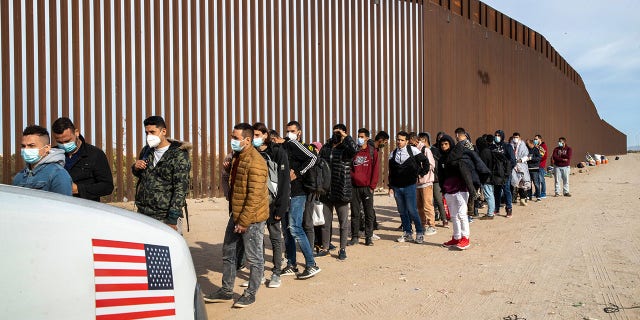 Immigrant men are taken into custody by U.S. Border Patrol agents at the U.S.-Mexico border Dec. 7, 2021, in Yuma, Ariz.