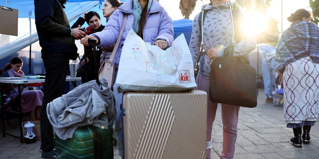 Ukrainians who are seeking asylum in the United States stand with their belongings at a makeshift encampment near the U.S.-Mexico border as the sun rises, amid the Russian invasion of Ukraine, on April 6, 2022 in Tijuana, Mexico.
