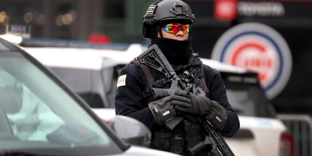 A police officer keeps watch as fans arrive for a chilly home opener at Wrigley Field to watch the Chicago Cubs play the Milwaukee Brewers on April 7, 2022, in Chicago.