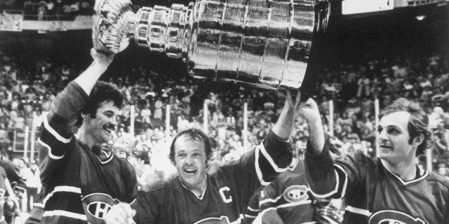 Yvan Cournoyer #12 of the Montreal Canadiens, hoist the Stanley Cup Trophy with help from teammates Yvon Lambert #10 and Guy Lafleur #10 after defeating the Boston Bruins 4-1 at the Boston Garden to take the National Hockey League Championship for the third straight year on May 25, 1978 in Boston, Massachusetts.