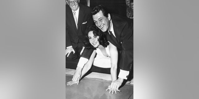 Elizabeth Taylor, with Rock Hudson, plants her hands in cement in the lobby of Grauman's Chinese Theater on Sept. 26th 1956, before the premiere of their film "Giant."