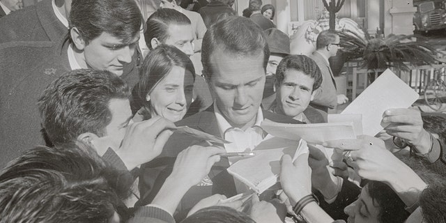 Autograph-hungry fans besiege American singer Pat Boone.  The artist was a teen idol in the 50s and 60s.
