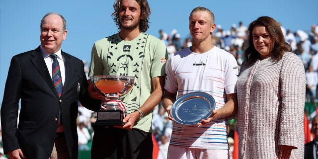 El príncipe Alberto y Melanie-Antoinette de Massy junto a Stefanos Tsitsipas de Grecia, quien sostiene el trofeo de ganador después de su partido con Alejandro Davidovich Fokina de España, en el Rolex Monte-Carlo Masters el 17 de abril de 2022 en Montecarlo, Mónaco.