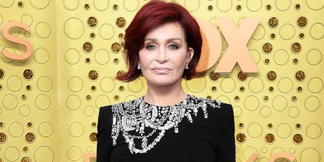 Sharon Osbourne with a short bob haircut and a black dress with stones on the top of the dress