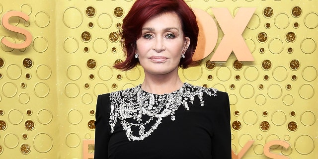 Sharon Osbourne with a short bob haircut and a black dress with stones on the top of the dress