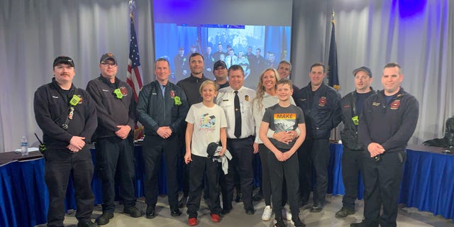 Jackson Gilchrist (center, in white T-shirt) and family pose with Salem Fire Department members in Salem, N.H. 