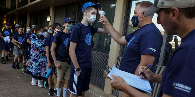 Daniel Bradstreet, a student at Michigan’s Clarkston Junior High School, has his temperature checked by school principal Adam Kern outside their hotel before boarding a tour bus with his classmates to go sightseeing in Washington, in Sterling, Virginia, U.S., June 18, 2021. REUTERS/Evelyn Hockstein