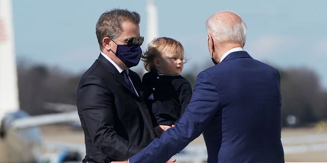 U.S. President Joe Biden turns back to assist his son Hunter Biden and grandson Beau while boarding Air Force One in a strong breeze as they depart Washington for travel to Wiilmington, Delaware at Joint Base Andrews, Maryland, U.S., March 26, 2021.