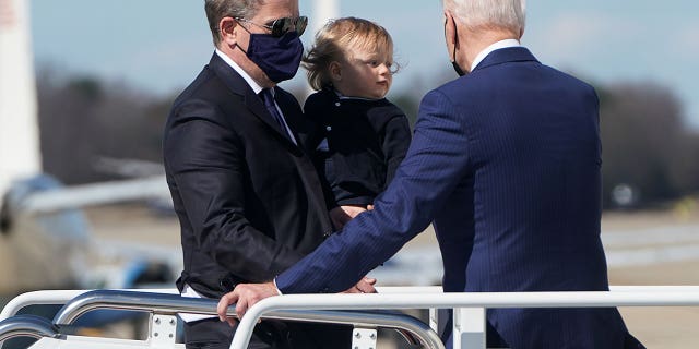 U.S. President Joe Biden turns back to assist his son Hunter Biden and grandson Beau while boarding Air Force One in a strong breeze as they depart Washington for travel to Wiilmington, Delaware at Joint Base Andrews, Maryland, U.S., March 26, 2021.