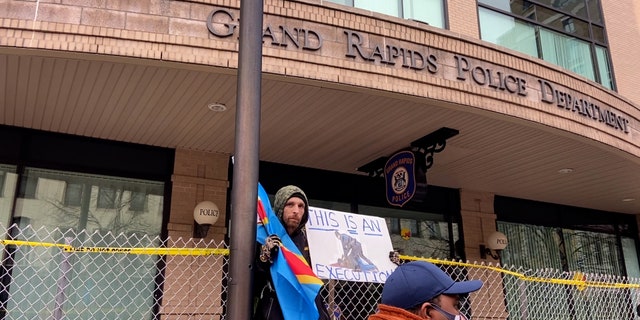 One protester holds a sign reading "This is an execution" outside a barricaded Grand Rapids Police Department