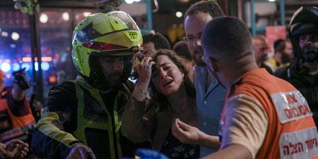 A woman reacts at the scene of a shooting attack In Tel Aviv, Israel, Thursday, April 7, 2022.