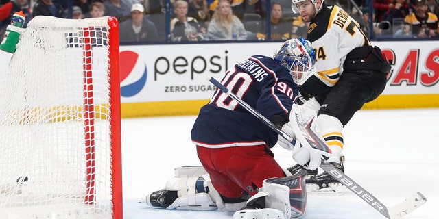 Boston Bruins forward Jake DeBrusk, right, scores past Columbus Blue Jackets goalie Elvis Merzlikins during the first period of an NHL hockey game in Columbus, Ohio, Monday, April 4, 2022.