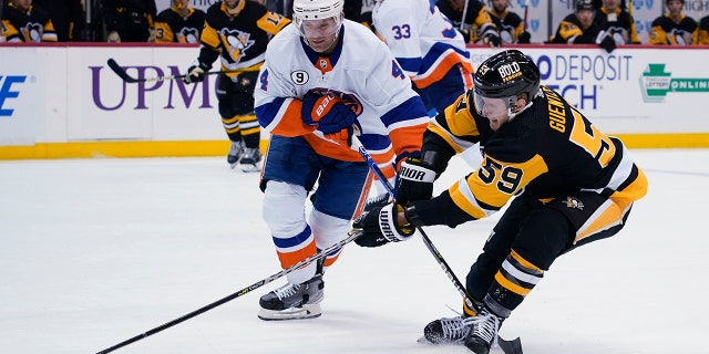 Pittsburgh Penguins' Jake Guentzel (59) tries to get the puck past New York Islanders' Andy Greene (4) during the second period of an NHL hockey game Thursday, abril 14, 2022, en Pittsburgh.