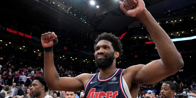 Philadelphia 76ers' Joel Embiid celebrates as Toronto Raptors forward OG Anunoby, links, walks past after Game 6 of an NBA basketball first-round playoff series Thursday, April 28, 2022, in Toronto.