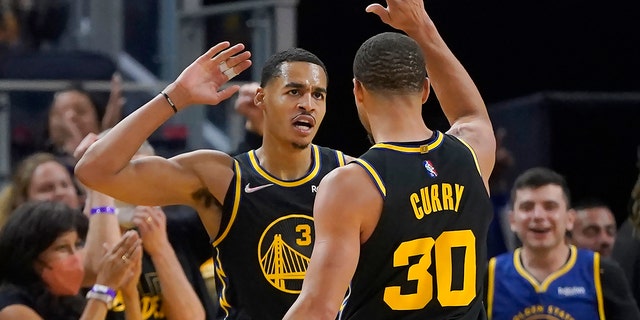 Golden State Warriors guard Jordan Poole congratulates guard Stephen Curry after scoring against the Denver Nuggets in San Francisco on April 16, 2022.