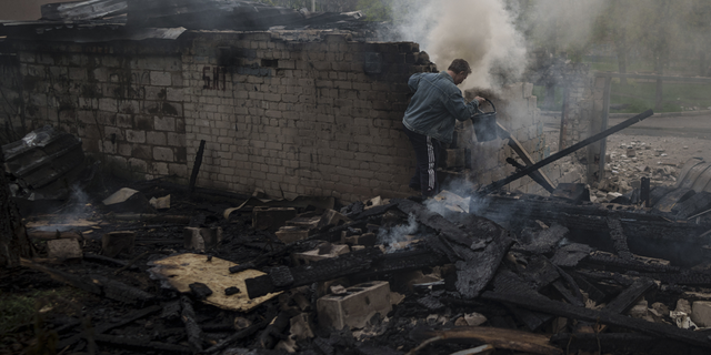 A man tries to extinguish a fire following a Russian bombardment at a residential neighborhood in Kharkiv, Ukraine, on Wednesday.