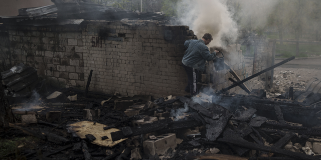 A man tries to extinguish a fire following a Russian bombardment at a residential neighborhood in Kharkiv, Ukraine, on Wednesday.