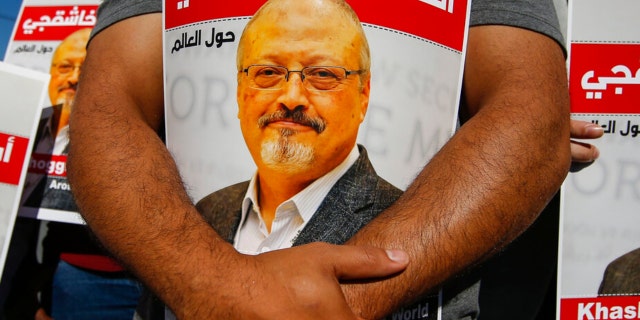 People hold posters of slain Saudi journalist Jamal Khashoggi, near the Saudi Arabian consulate in Istanbul, October 2, 2020, marking the second anniversary of his death. 