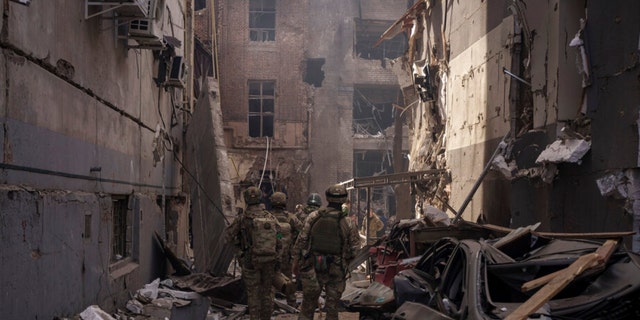 Ukrainian servicemen walk among debris of damaged buildings after a Russian attack in Kharkiv, Ukraine, Saturday, April 16, 2022.