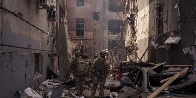 Ukrainian servicemen walk among debris of damaged buildings after a Russian attack in Kharkiv, Ukraine, Saturday, April 16, 2022. 