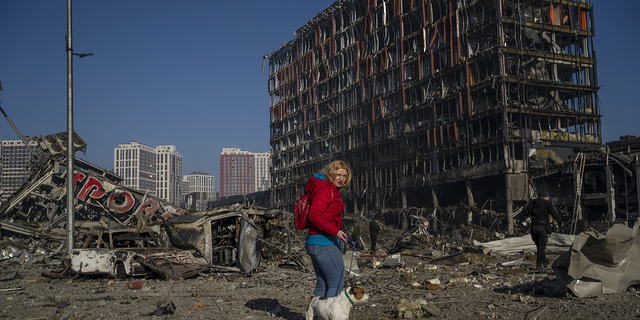 Irina Zubchenko pasea a su perro Max en medio de la devastación causada por el bombardeo de un centro comercial en Kiev, Ucrania, el lunes.