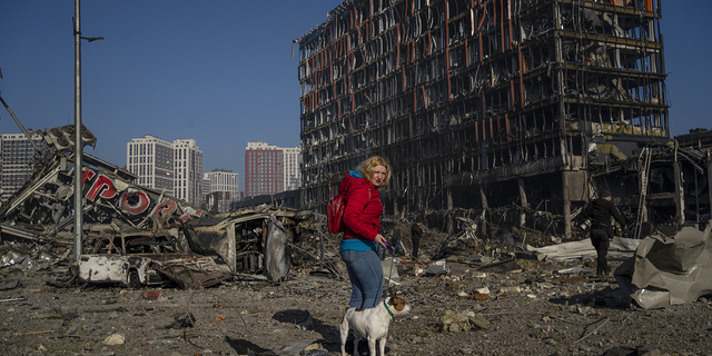 Irina Zubchenko pasea a su perro Max en medio de la devastación causada por el bombardeo de un centro comercial en Kiev, Ucrania, el lunes.