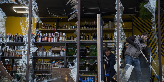 Employees at a liquor store clean glass broken following the explosion on Thursday, April 28.