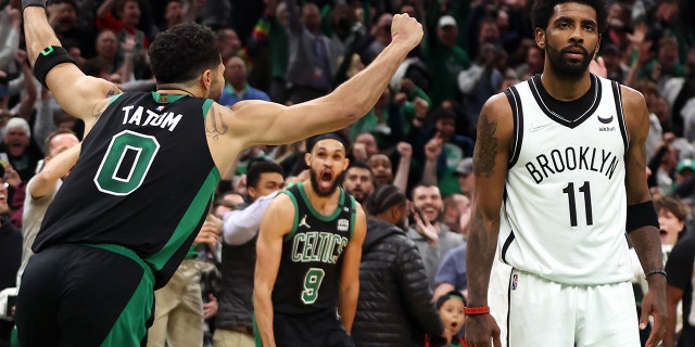 Jayson Tatum of the Boston Celtics celebrates the game-winning basket as Kyrie Irving of the Brooklyn Nets looks on at TD Garden on April 17, 2022, in Boston.